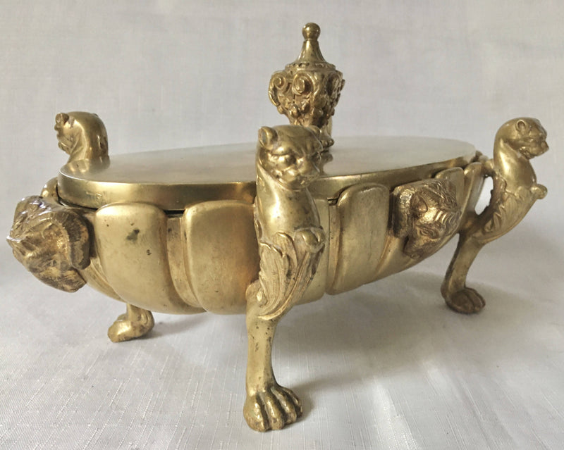 Regency period gilt bronze inkstand raised on lioness paw feet and adorned with ram masks.