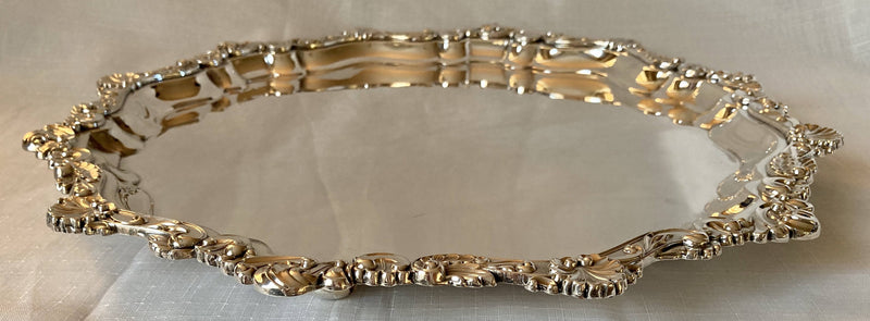 Large silver plated circular salver with shell and scroll border, raised on bun feet.