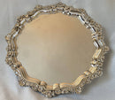Large silver plated circular salver with shell and scroll border, raised on bun feet.